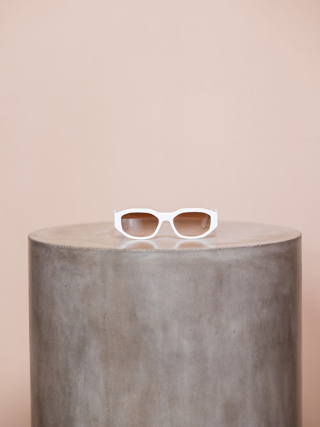 White sunglasses on podium against pink background