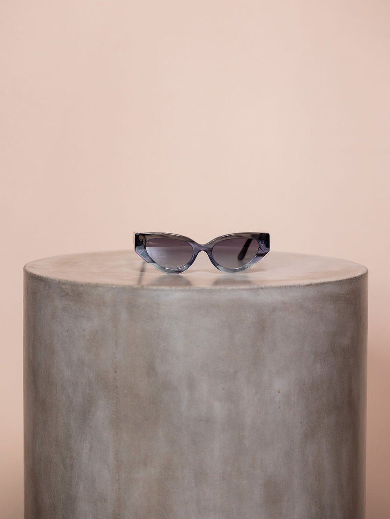 Gray sunglasses on podium against pink background