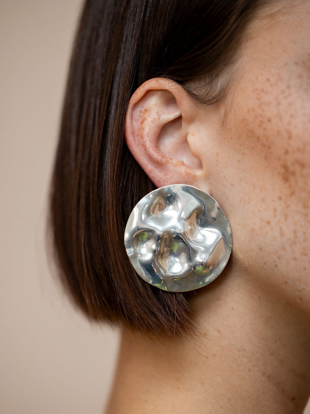 Woman wearing textured silver disc earrings