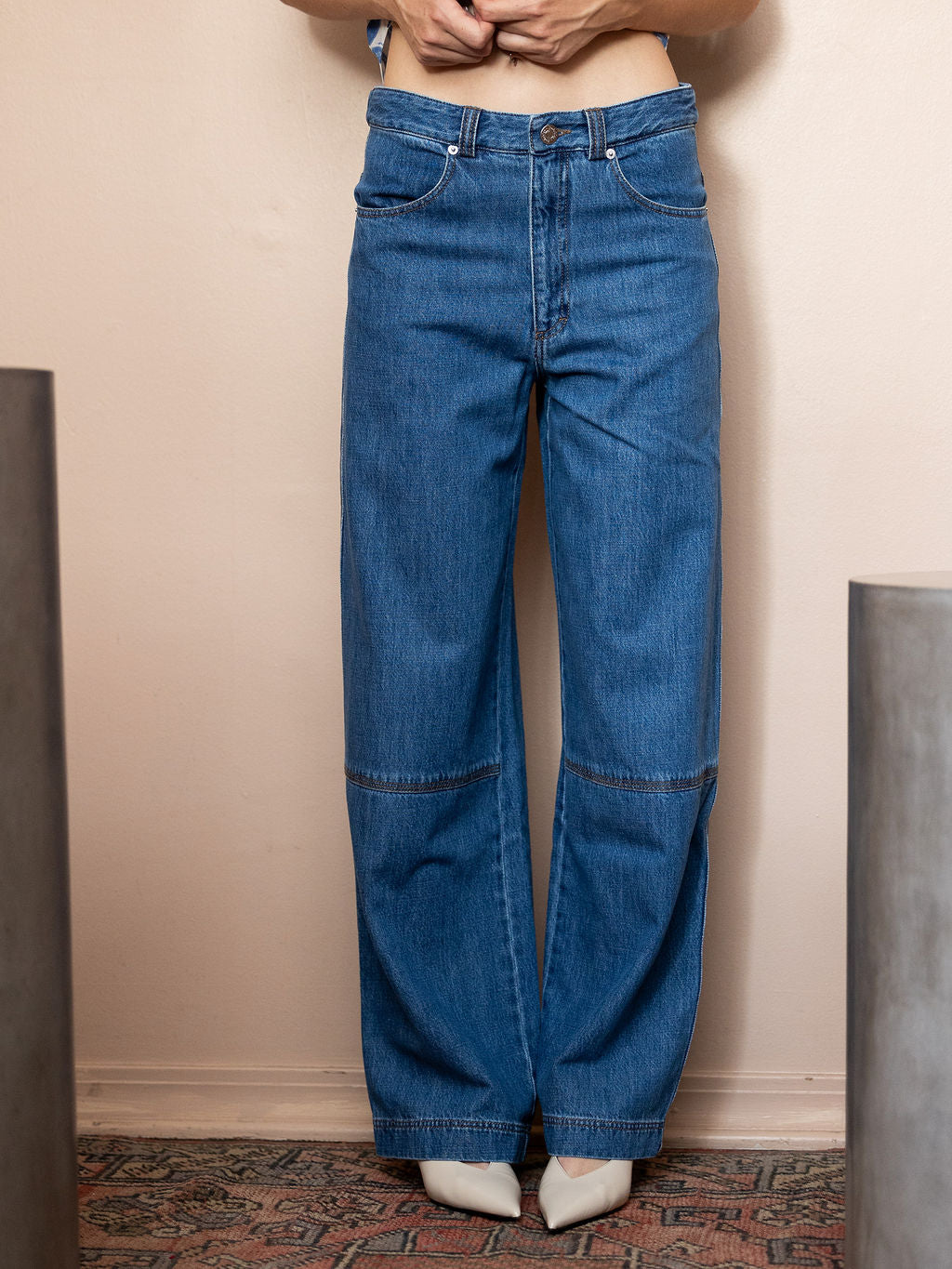 Woman wearing  blue jeans against pink background