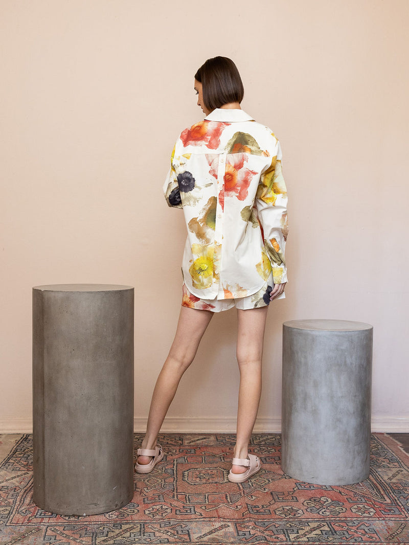 Woman wearing cream floral top and matching shorts against pink background