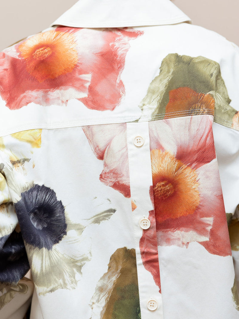 Woman wearing cream floral top and matching shorts against pink background