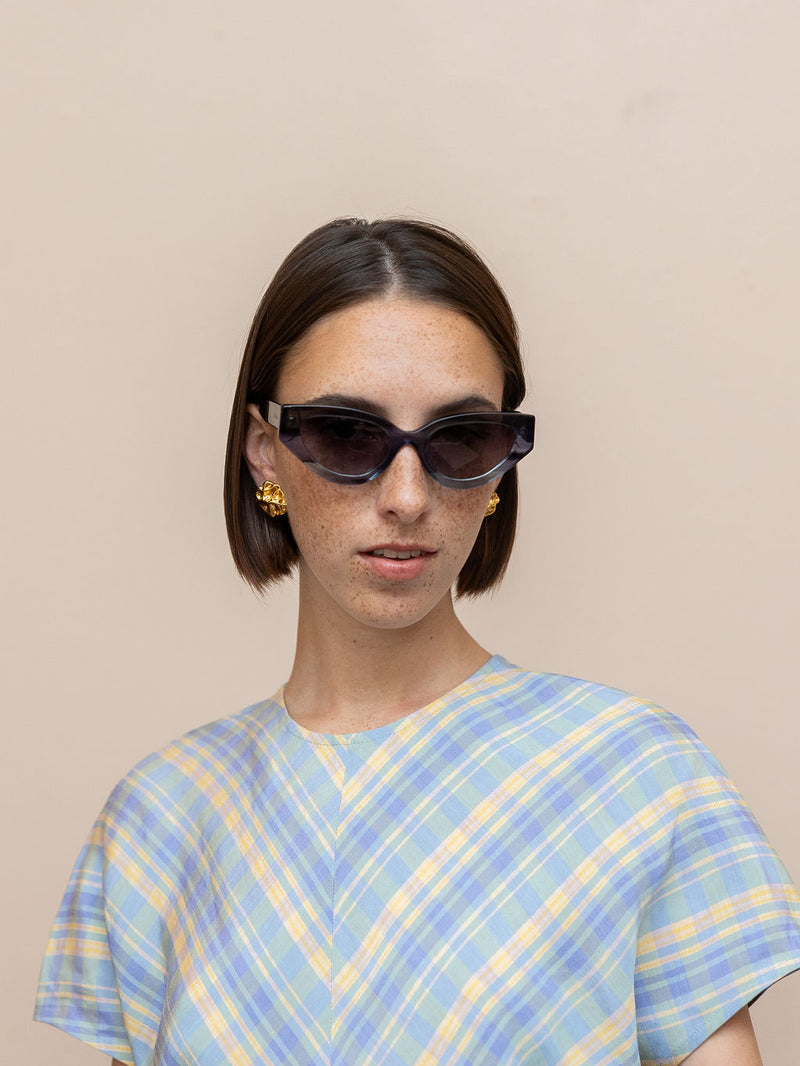 Woman wearing gray sunglasses against pink background