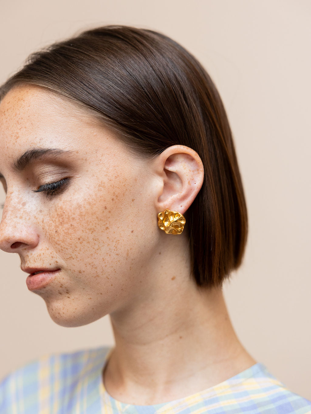 Woman wearing small gold textured earrings