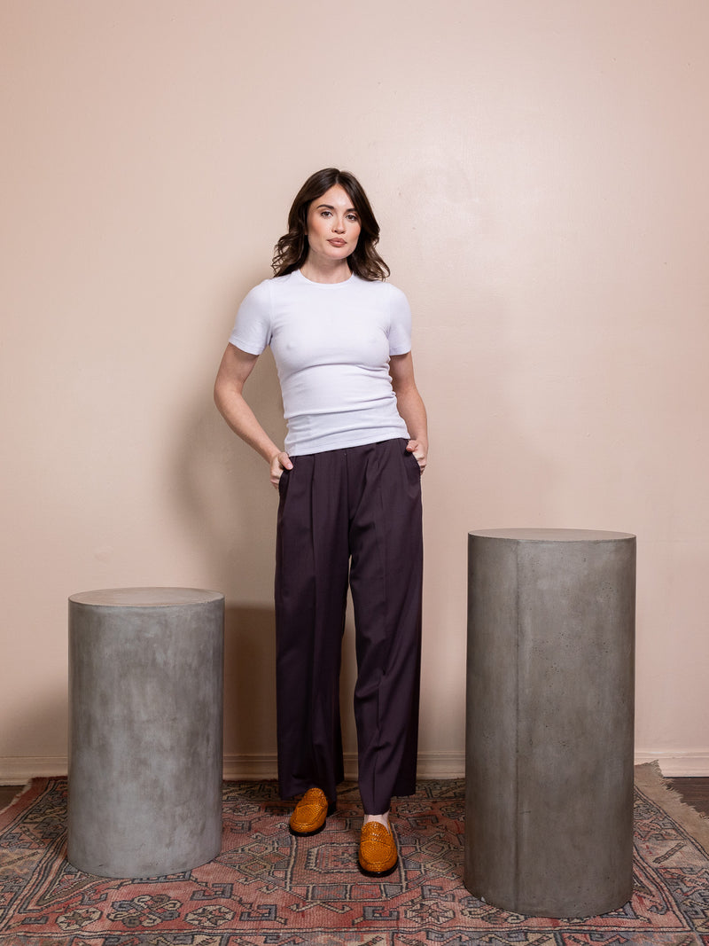 Woman in purple top and purple pants against pink background