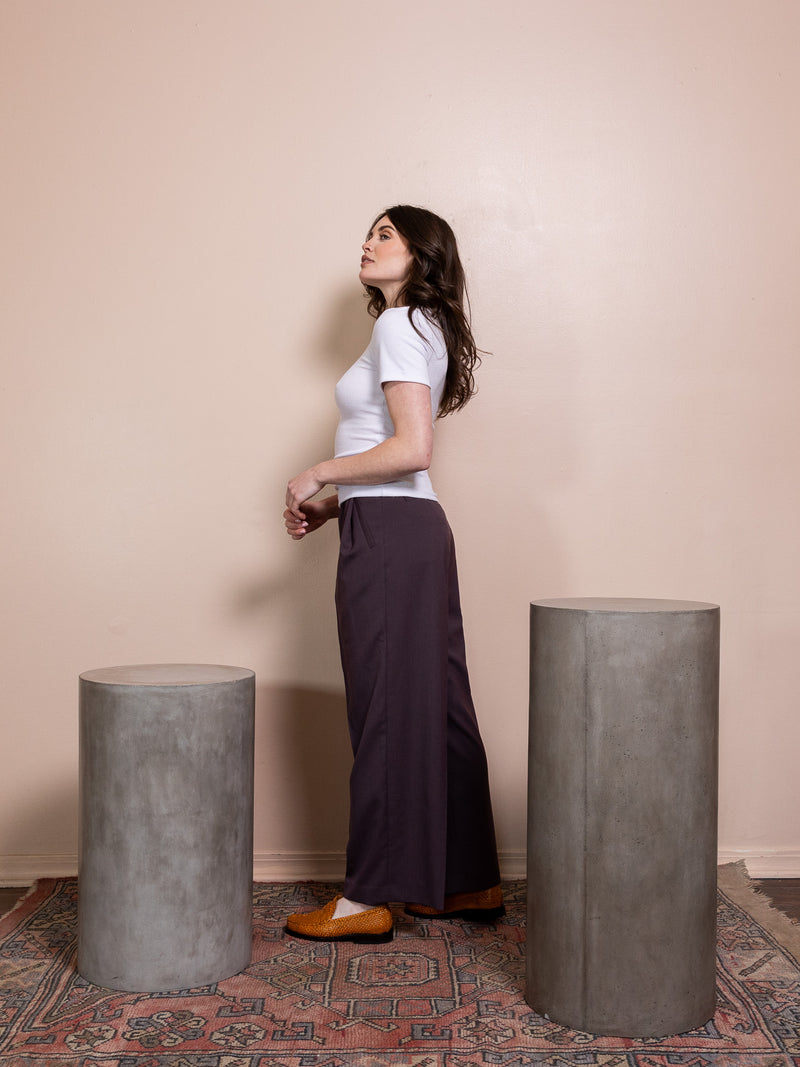 Woman in purple top and purple pants against pink background