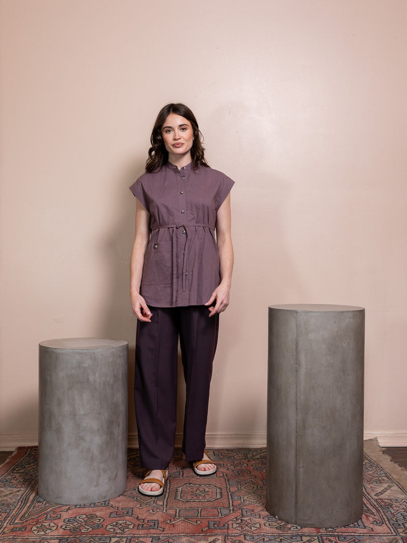 Woman in purple top and purple pants against pink background