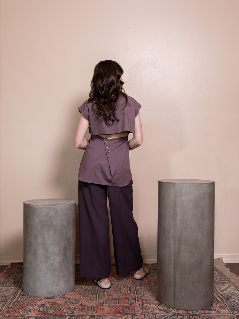 Woman in purple top and purple pants against pink background