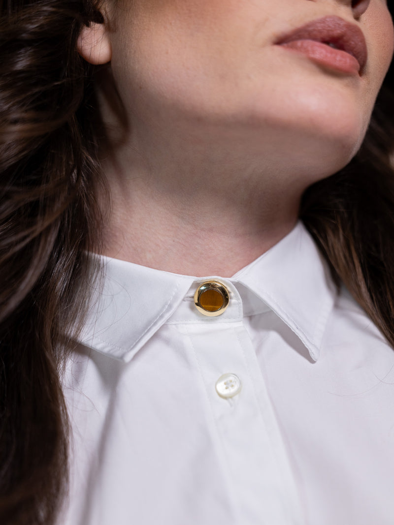 Tiger's eye and gold button cover on white shirt.