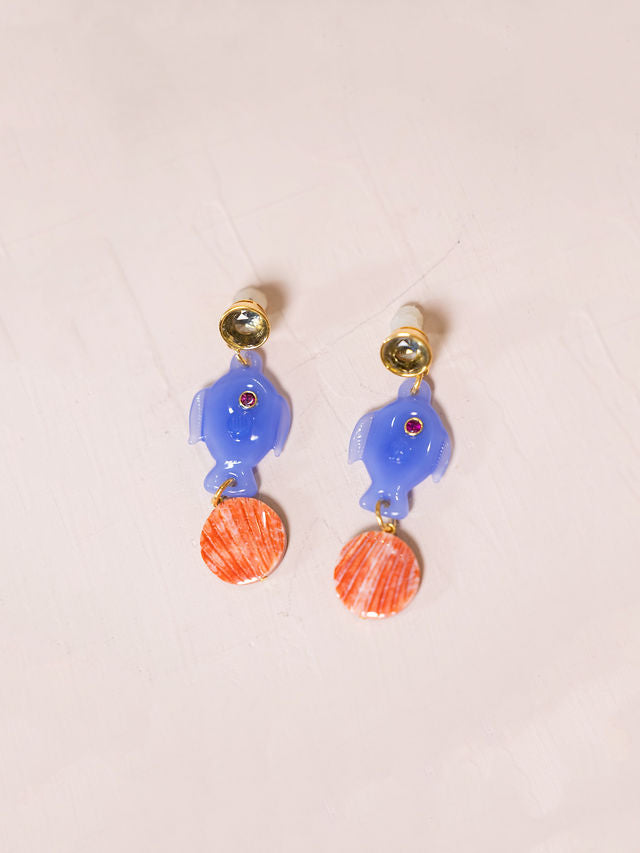 Earrings with fish and shells against pink background