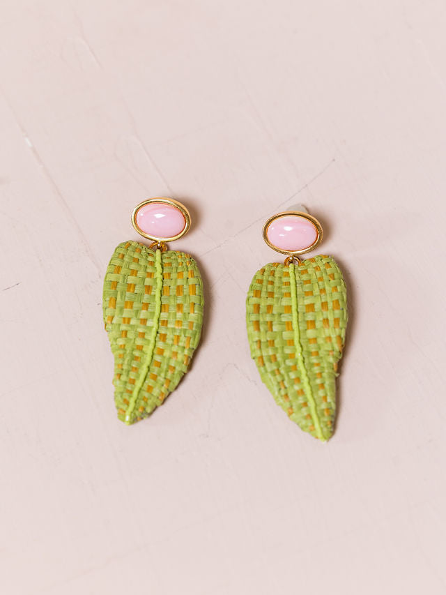 Long earrings with woven leaves against pink background