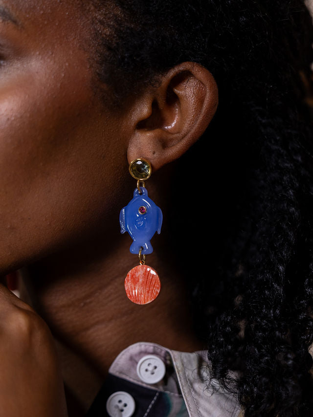 Woman wearing layered earrings with fish and shell design