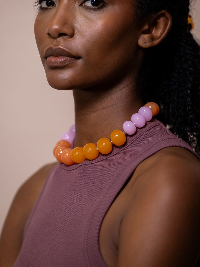 Woman wearing necklace made of large orange and pink beads